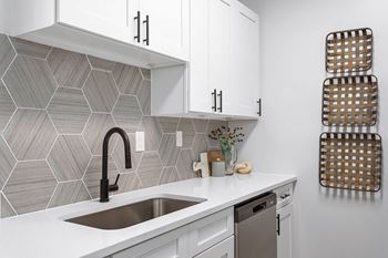 a small kitchen with white cabinets and a black faucet